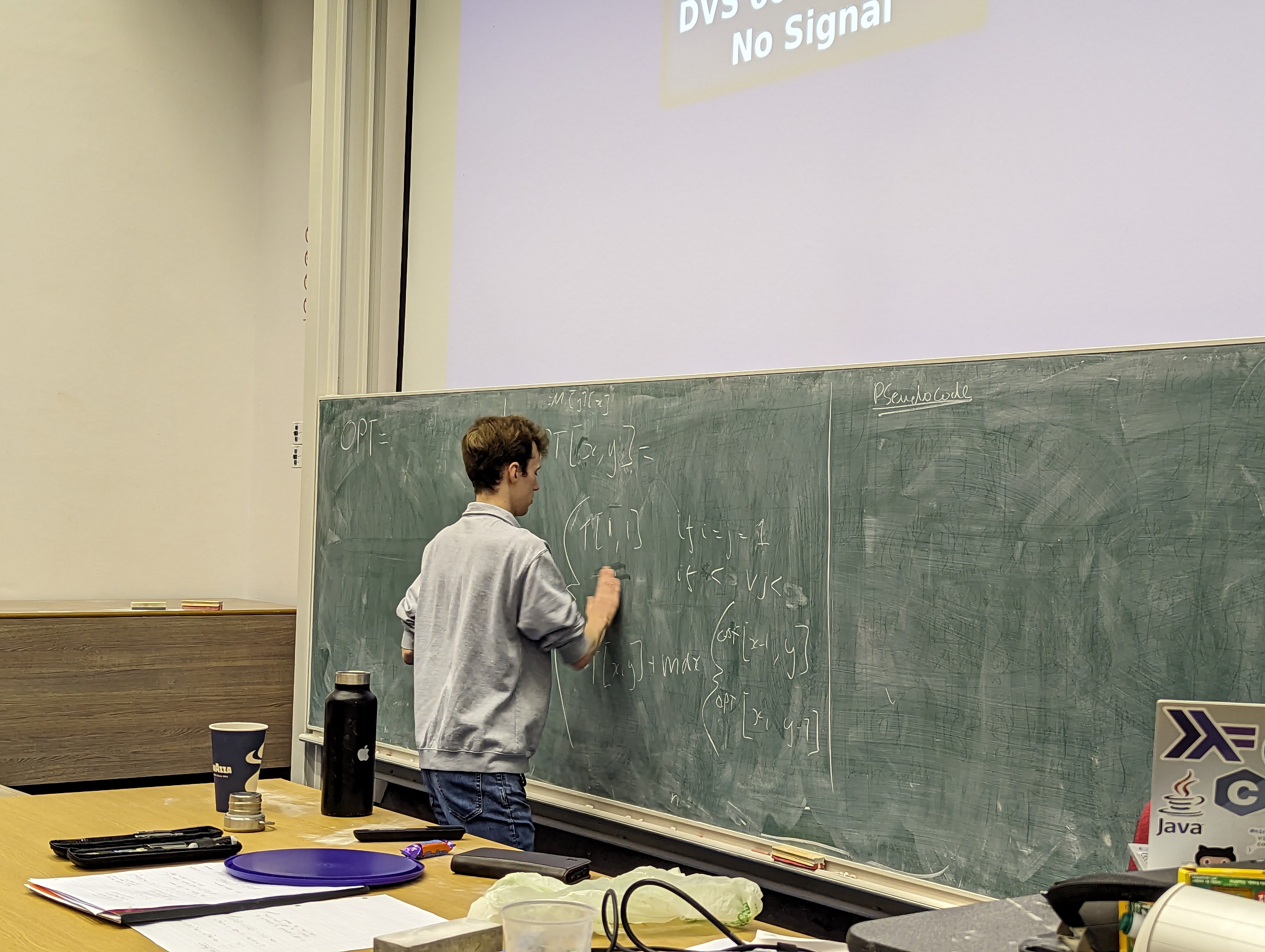 A photo of me writing a Bellman-Ford equation on a blackboard.