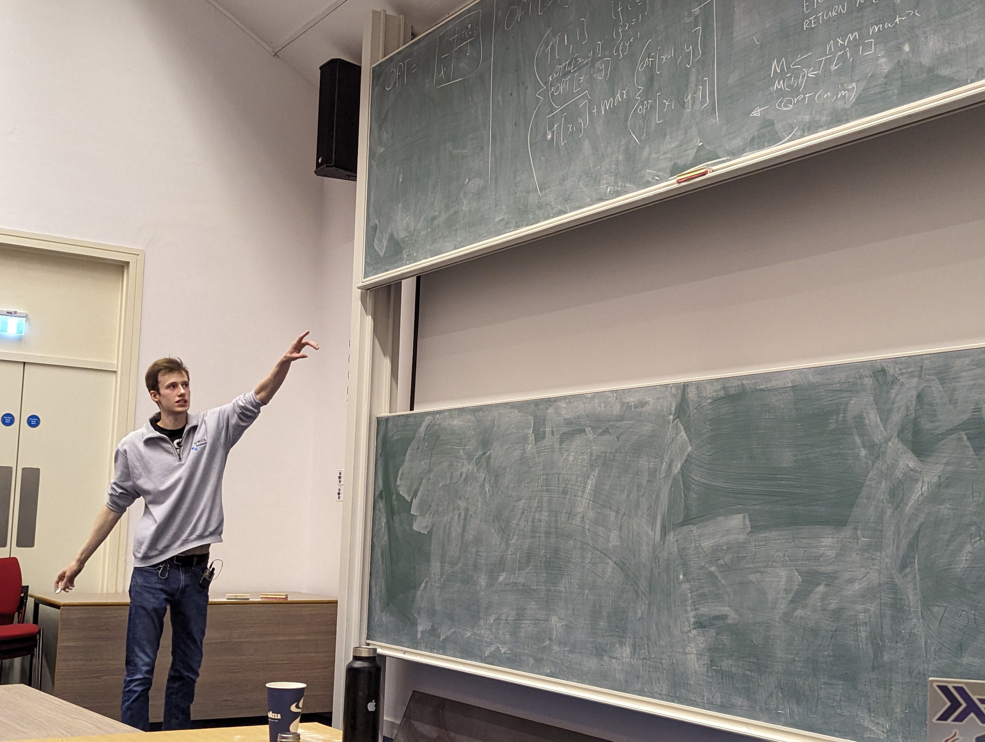 A photo of me pointing at a blackboard.